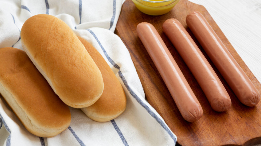 RC2B62 RC2B62 Ingredients for making hot dogs: sausages, hot-dog buns and mustard on white wooden surface, side view. Closeup.